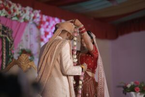 A bride and groom exchange garlands during a traditional Indian wedding ceremony.